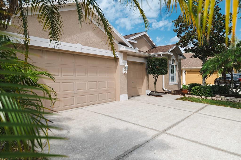 A beige house with a three-car garage and a concrete driveway under a blue sky — 9020 N RIVER ROAD, TAMPA, FL