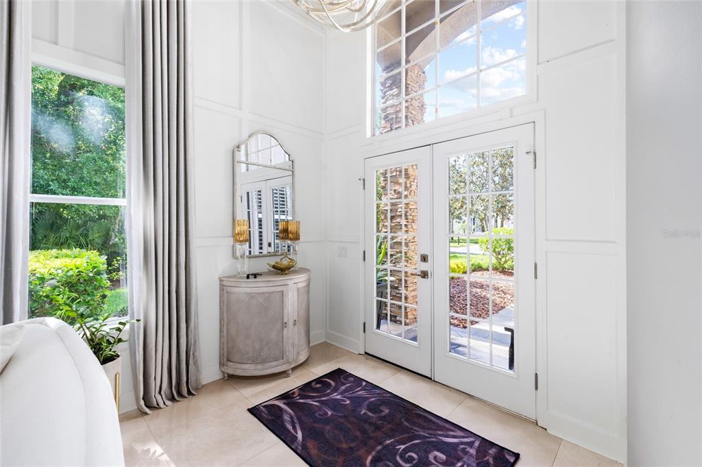 A bright entryway features a double glass door, tall windows, white paneled walls, and tile flooring — 9642 GRETNA GREEN DRIVE, TAMPA, FL