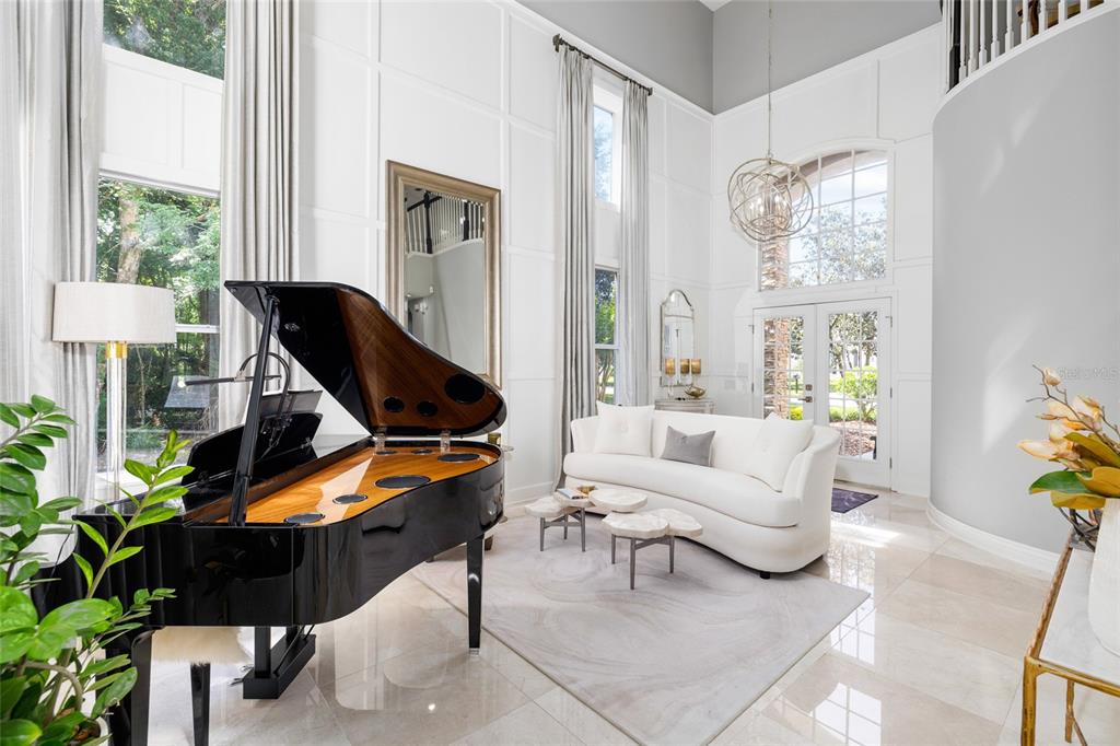 A grand foyer features a black piano, white sofa, tall windows, and high paneled walls — 9642 GRETNA GREEN DRIVE, TAMPA, FL
