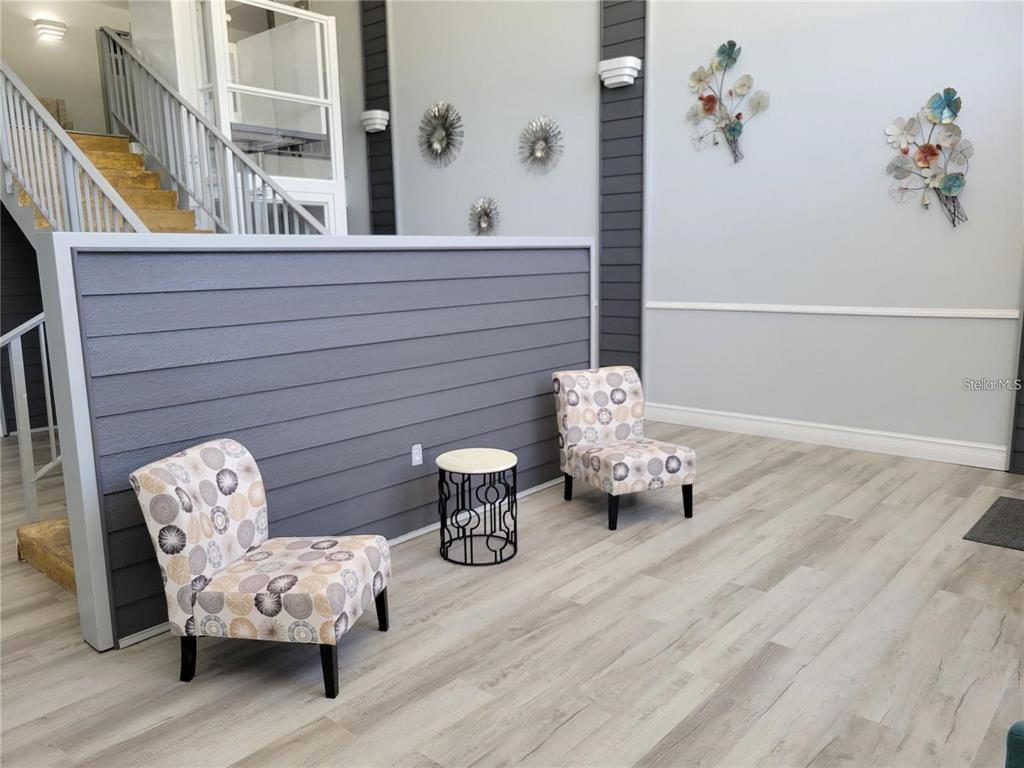 A waiting area features two patterned armchairs, a small side table, and wood-look flooring — 21320 BRINSON AVENUE UNIT 105, PORT CHARLOTTE, FL