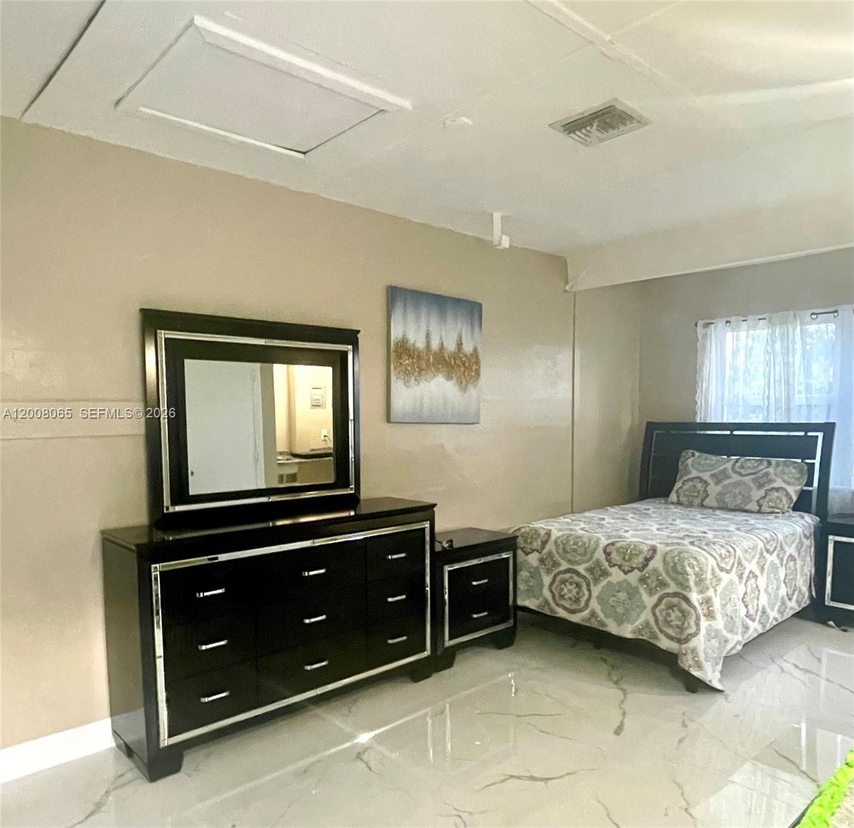 A bedroom features a black dresser with a mirror, a bed, and light-colored tile flooring — 1537 NE 30th Ct # 0, Pompano Beach FL 33064, POMPANO BEACH, FL