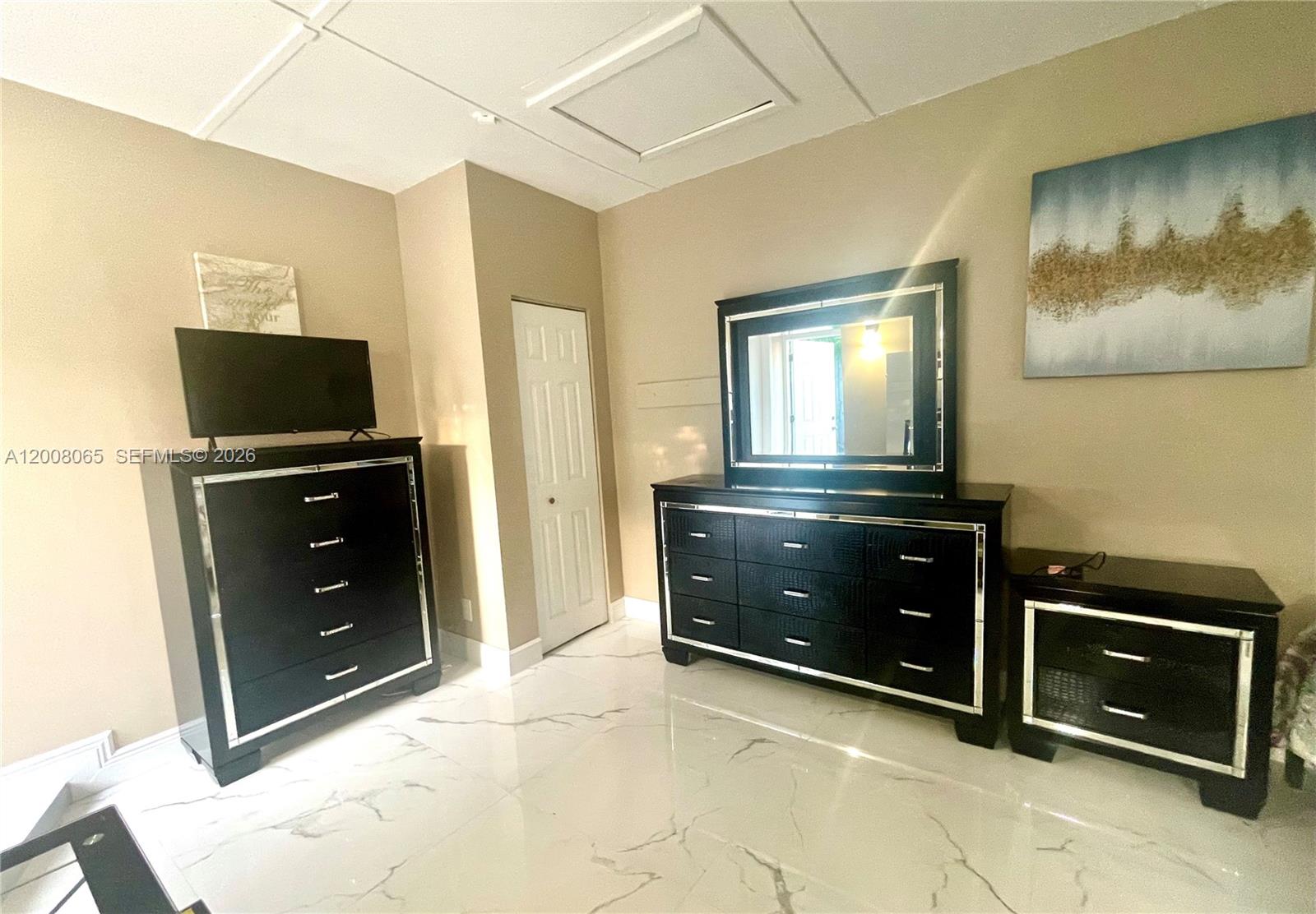 A bedroom features black furniture, a large mirror, and white marble-patterned tile flooring — 1537 NE 30th Ct # 0, Pompano Beach FL 33064, POMPANO BEACH, FL