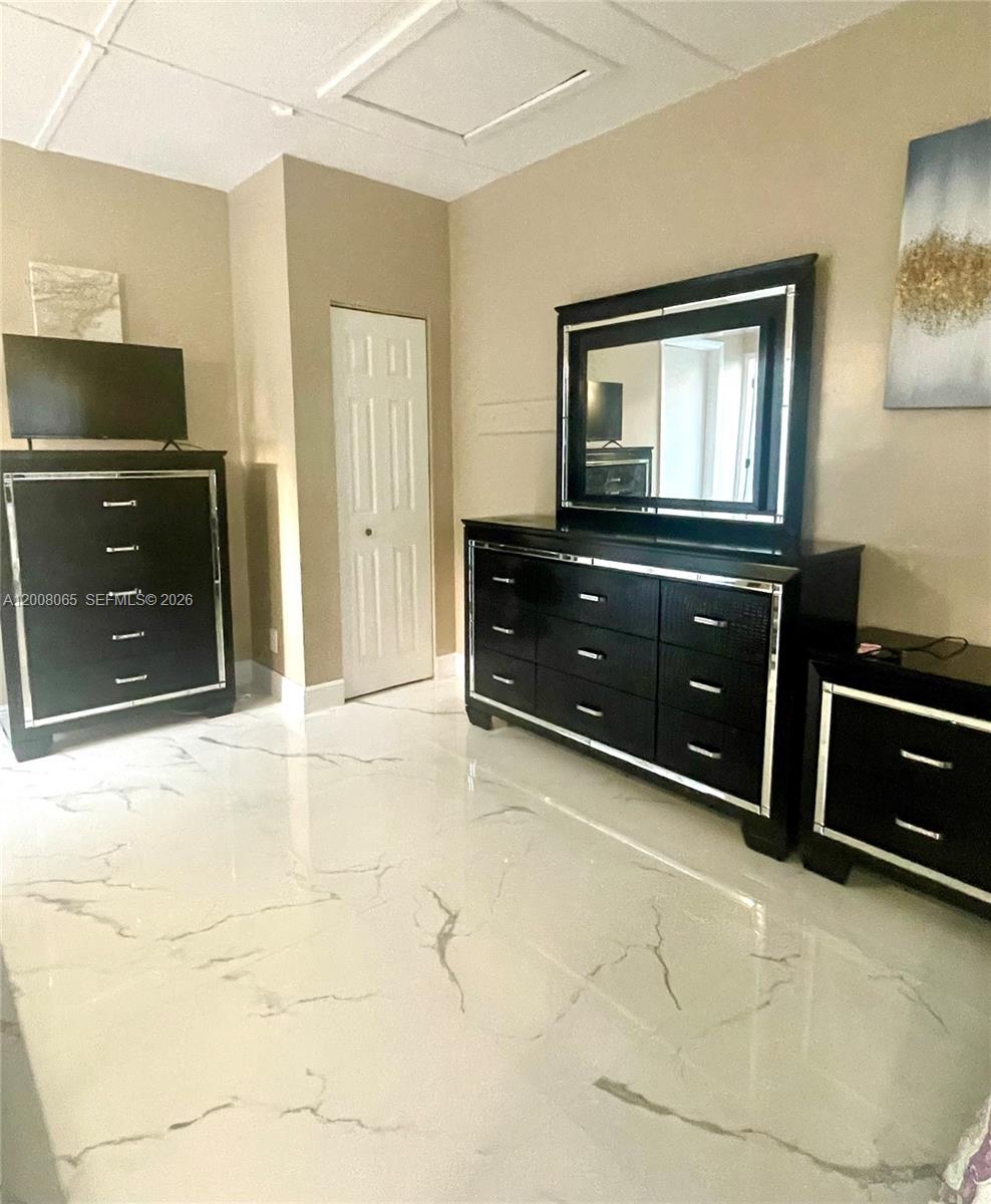 A bedroom features black furniture, a large mirror, and white marble-patterned tile flooring — 1537 NE 30th Ct # 0, Pompano Beach FL 33064, POMPANO BEACH, FL