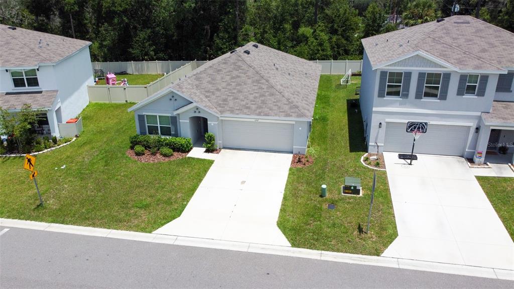 An aerial view shows a single-story house with a driveway situated between two-story homes — 6747 SE 3RD LOOP, OCALA, FL