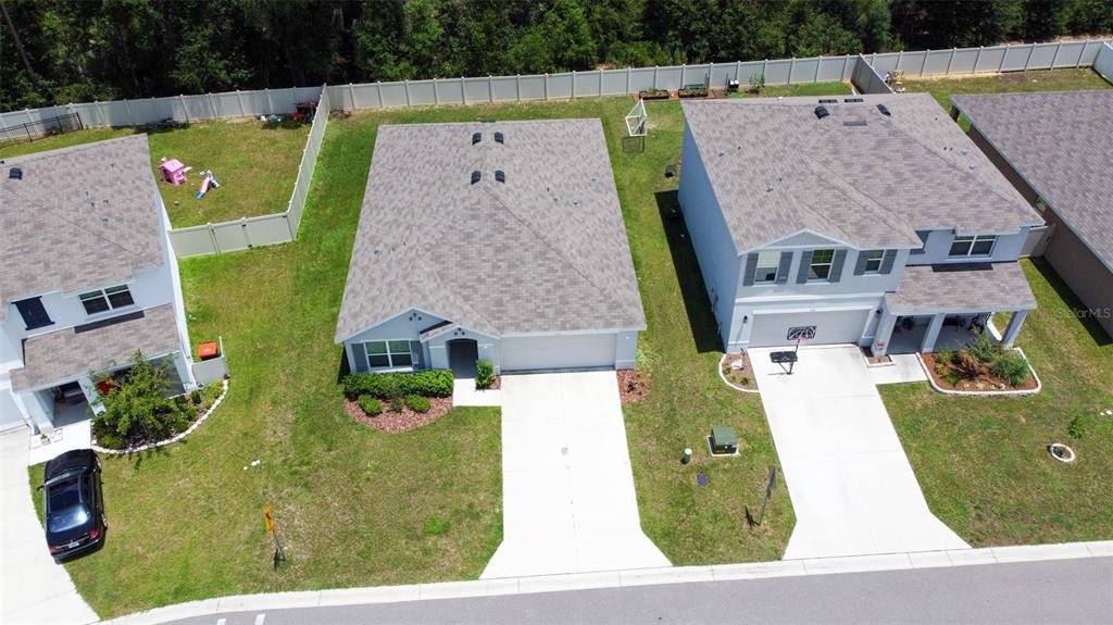 An aerial view shows three suburban houses with driveways and fenced backyards along a street — 6747 SE 3RD LOOP, OCALA, FL