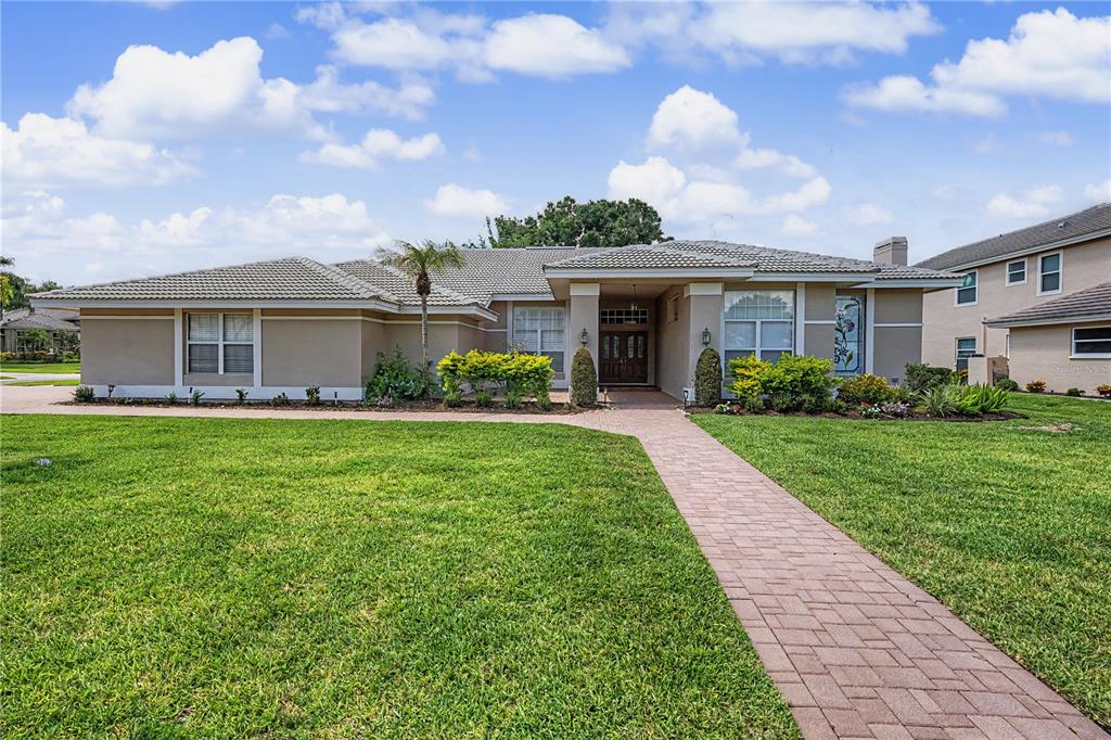 A single-story house with a tiled roof, beige stucco exterior, and a brick walkway — 1319 FORESTEDGE BOULEVARD, OLDSMAR, FL