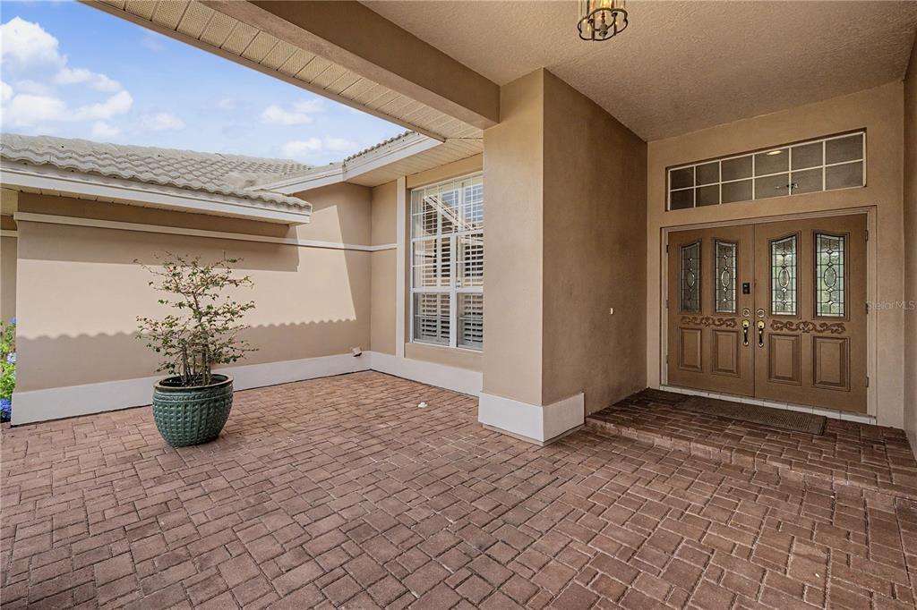 A paved entryway features a potted plant, a large window, and double front doors — 1319 FORESTEDGE BOULEVARD, OLDSMAR, FL