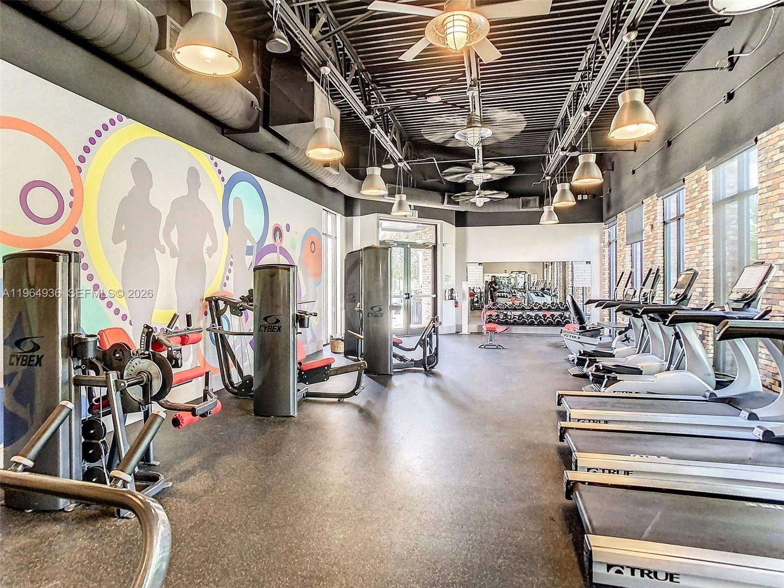 A gym features Cybex weight machines, rows of treadmills, and a colorful mural on the wall — 742 Langboat Dr, Davenport FL 33896, DAVENPORT, FL