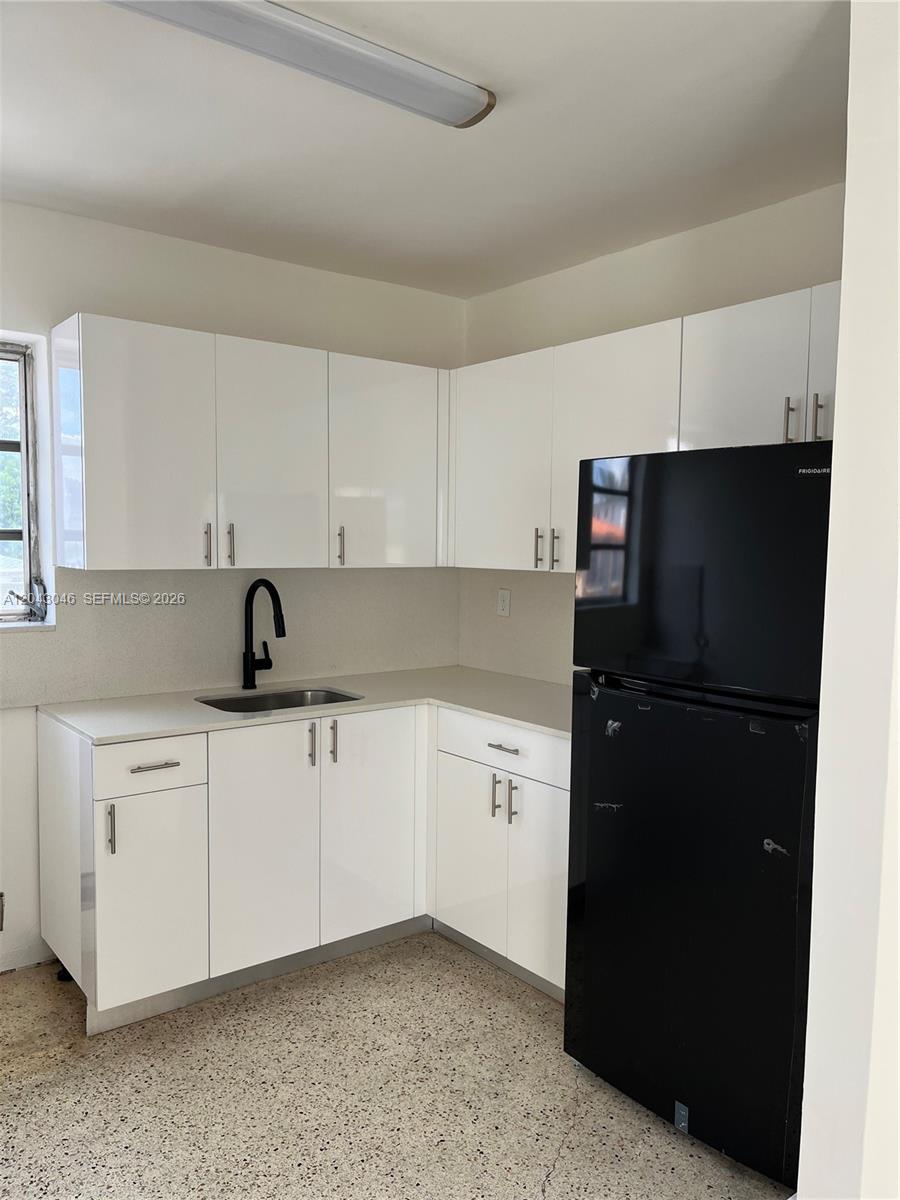 A kitchen features white flat-panel cabinets, light countertops, a black faucet, and a black refrigerator — 2010 SW 6th St # 4, Miami FL 33135, MIAMI, FL