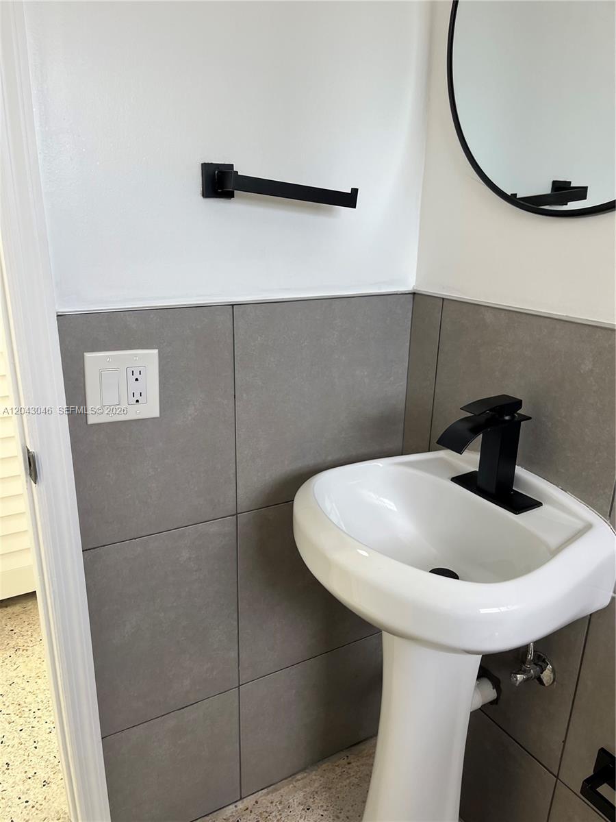 A bathroom features a pedestal sink, matte black fixtures, and gray tiled walls — 2010 SW 6th St # 4, Miami FL 33135, MIAMI, FL