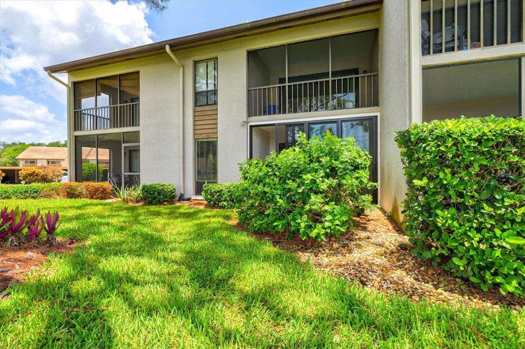 The exterior of a two-story apartment building features screened balconies and landscaped green space — 3053 TAYWOOD MEADOWS UNIT 3, SARASOTA, FL