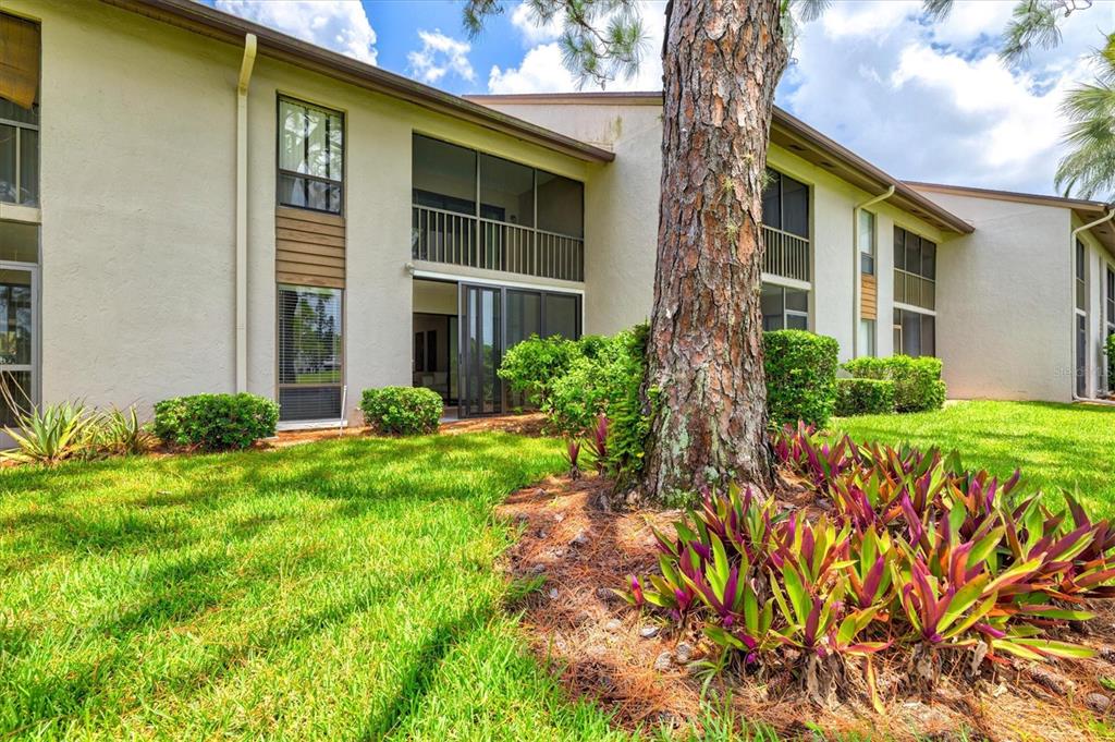 A two-story apartment building exterior features a screened balcony, sliding glass doors, and landscaping — 3053 TAYWOOD MEADOWS UNIT 3, SARASOTA, FL