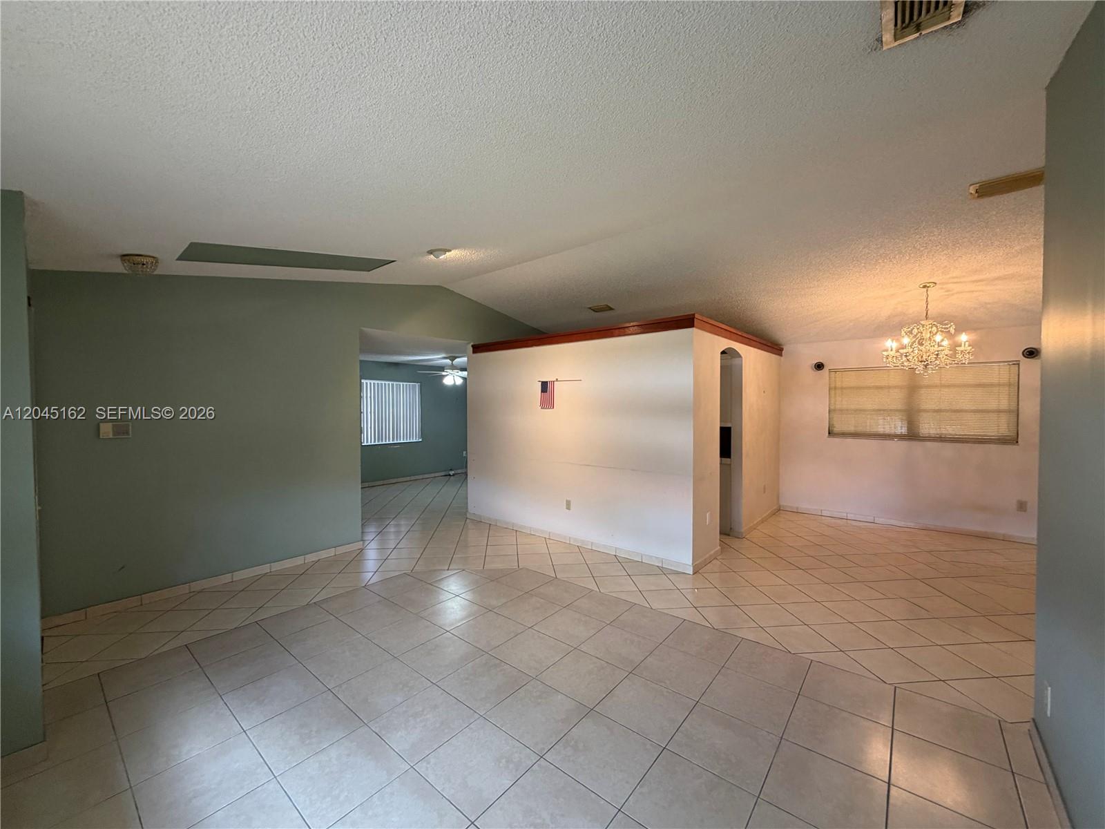 An open living area features light-colored tile flooring, a central partition wall, and a chandelier — 3262 SW 139th Pl, Miami FL 33175, MIAMI, FL