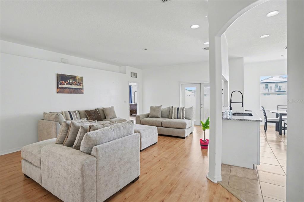 A living room with light wood floors, neutral sofas, and an adjacent kitchen area — 3614 TRAPNELL RIDGE DR, PLANT CITY, FL