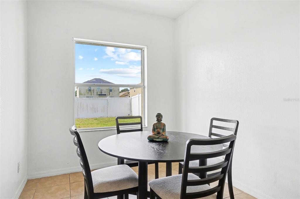 A dining area features a round black table, four chairs, and a window overlooking a yard — 3614 TRAPNELL RIDGE DR, PLANT CITY, FL