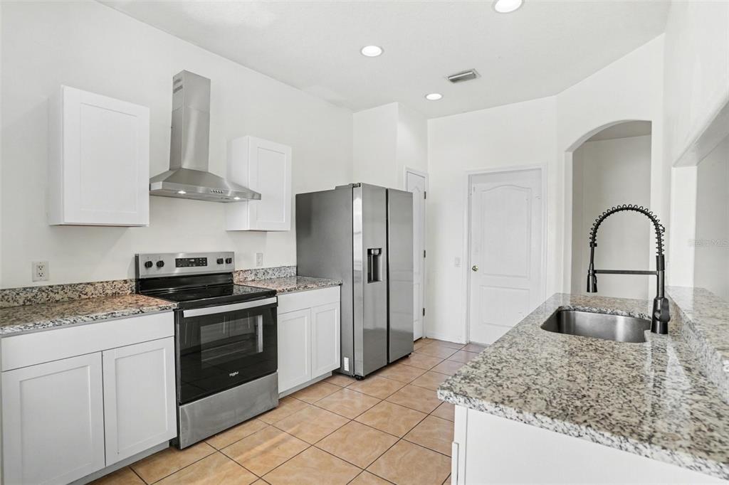 A kitchen features white cabinets, granite countertops, stainless steel appliances, and tile flooring — 3614 TRAPNELL RIDGE DR, PLANT CITY, FL