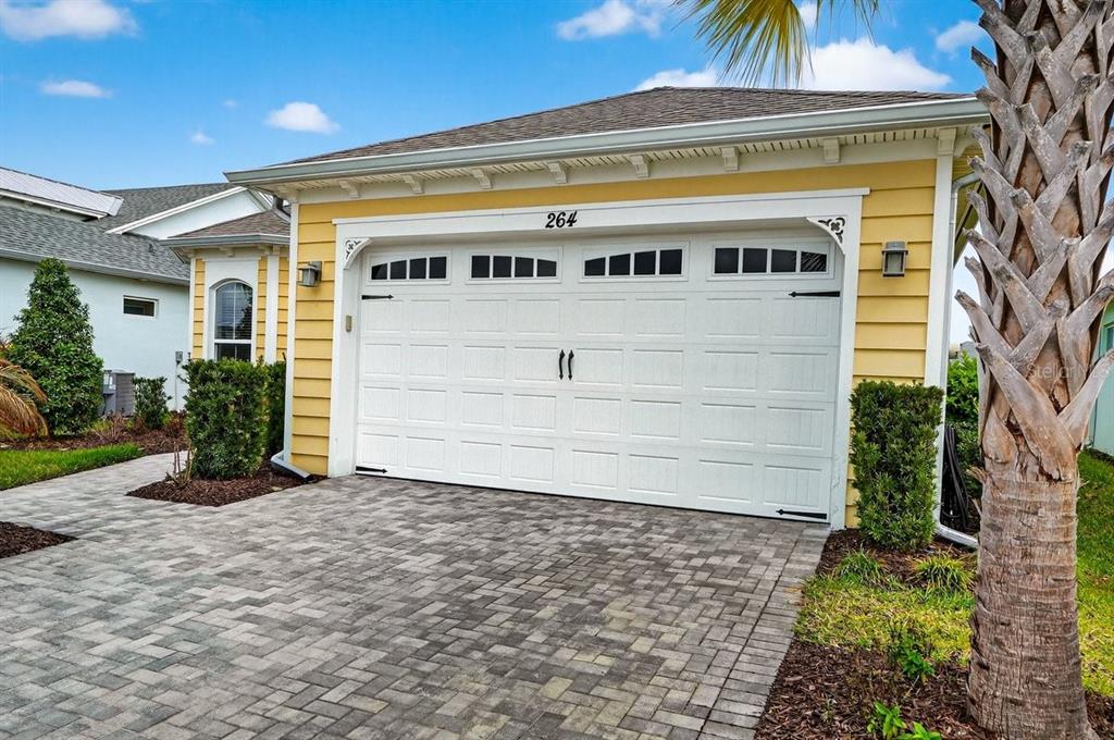 A yellow house exterior features a white two-car garage door and a paved driveway — 264 MARGARITAVILLE AVENUE, DAYTONA BEACH, FL