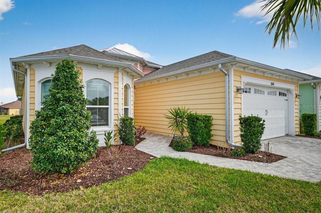 The exterior of a yellow house with a white garage door and a paved walkway — 264 MARGARITAVILLE AVENUE, DAYTONA BEACH, FL