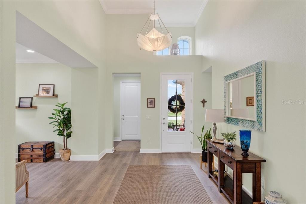 A bright entryway features high ceilings, a chandelier, wood-look flooring, and a white front door — 264 MARGARITAVILLE AVENUE, DAYTONA BEACH, FL