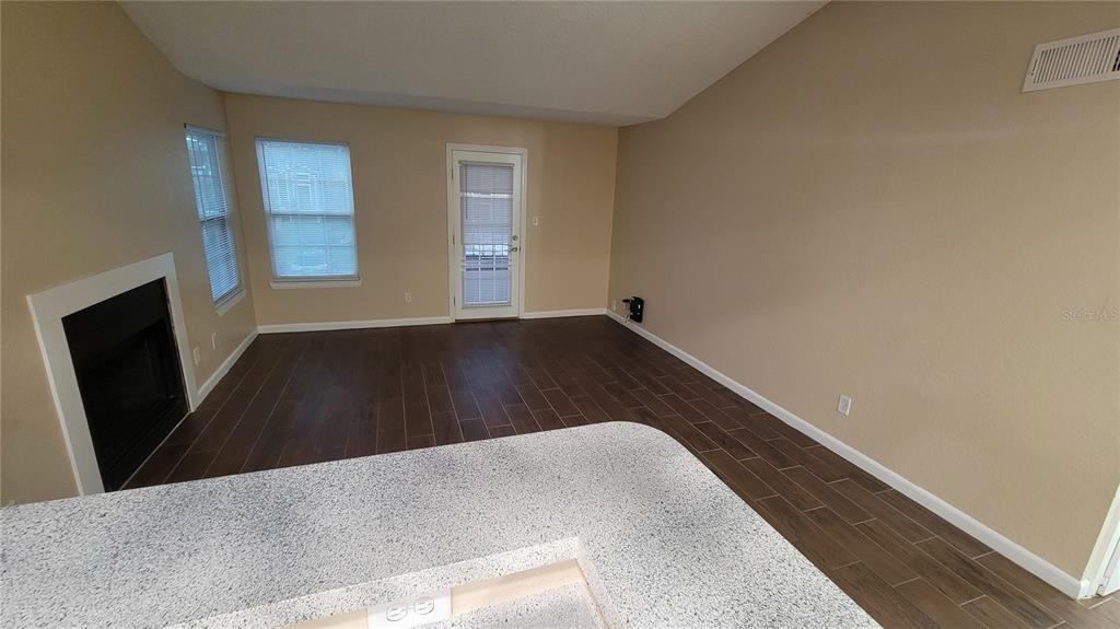 A living room with wood-look tile flooring, a fireplace, and a glass door to outside — 5600 DEVONBRIAR WAY UNIT N202, ORLANDO, FL