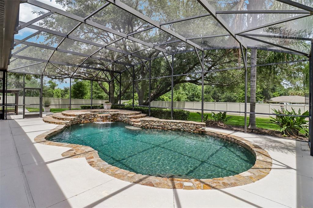 A screened-in patio features a freeform swimming pool with a stone-accented raised spa and waterfall — 34028 MATTHEWS COVE, LEESBURG, FL