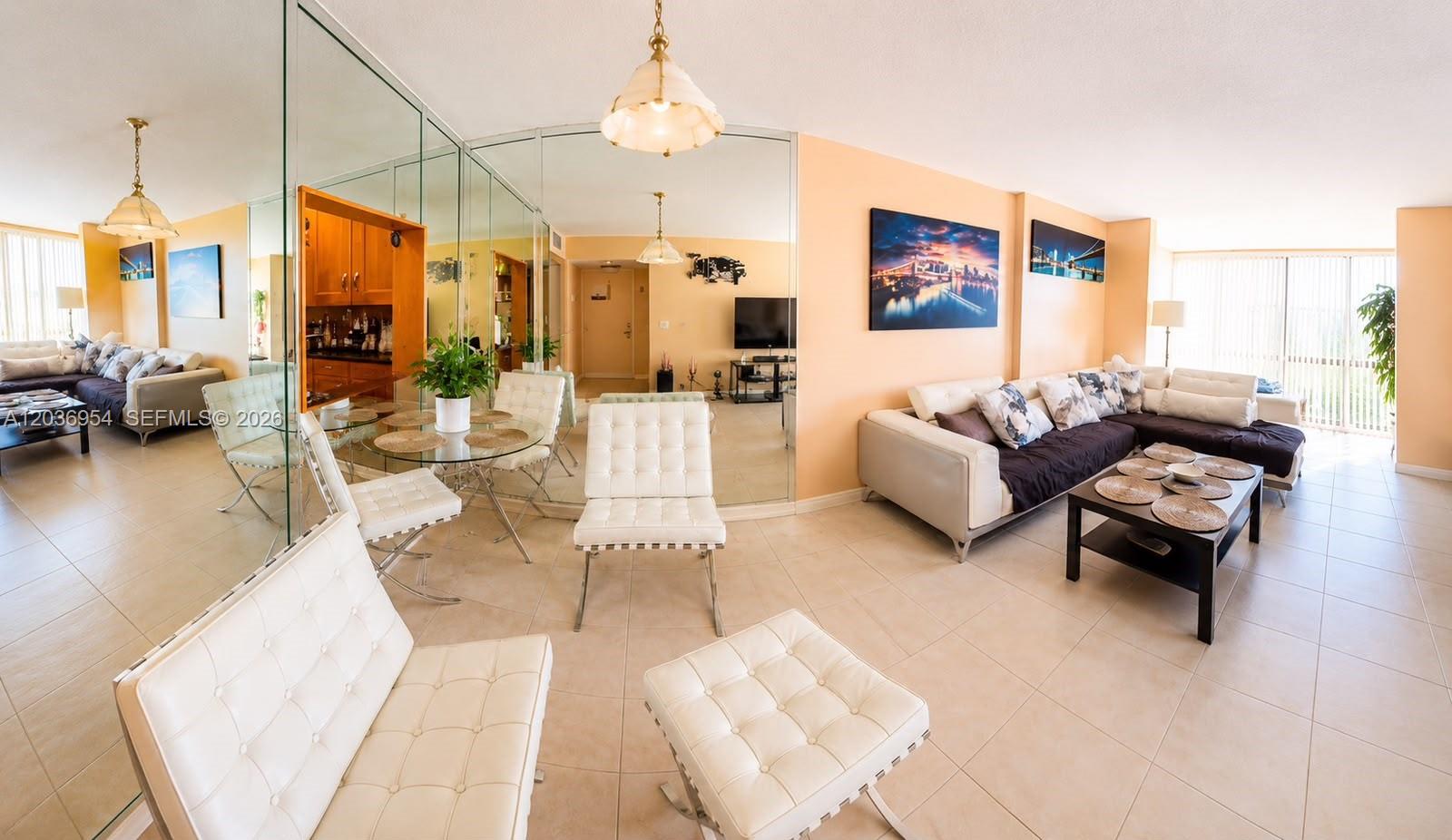 A living and dining area features tiled floors, mirrored walls, and white tufted furniture — 1000 Parkview Dr # 505, Hallandale Beach FL 33009, HALLANDALE BEACH, FL