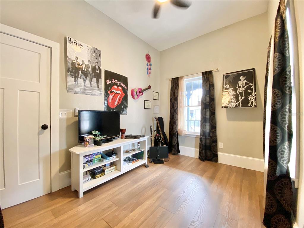 A room with light wood floors, a white media console, and music-themed wall decor — 908 E 20TH AVENUE, TAMPA, FL