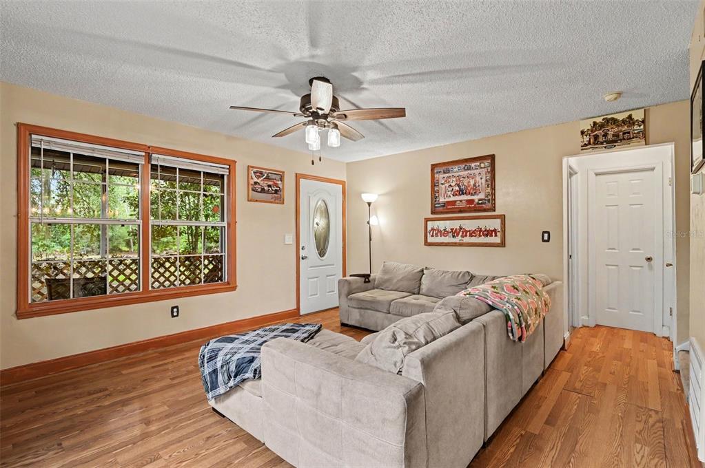 A living room features wood-look flooring, a ceiling fan, and a gray sectional sofa — 490 PINE WOODS ROAD, ORMOND BEACH, FL