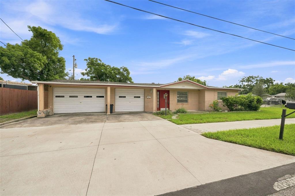 A single-story house with a two-car garage, tan exterior, and a red front door — 4126 WIGGINS DRIVE, NEW PORT RICHEY, FL