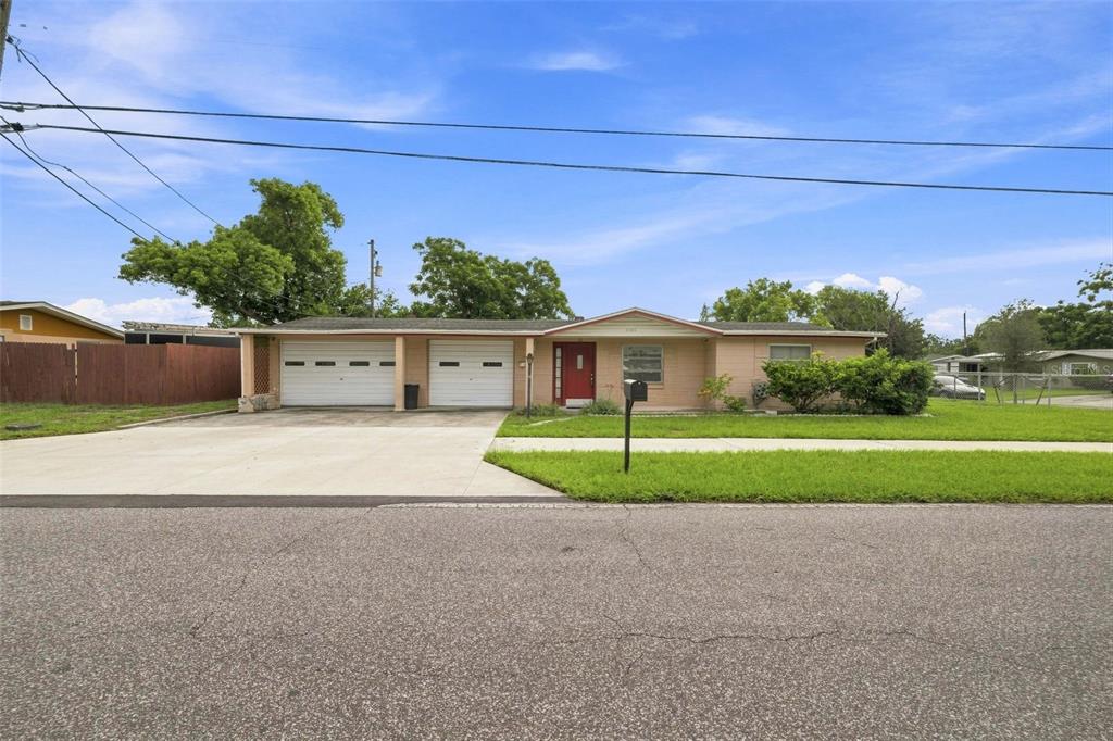 A single-story house with a two-car garage, a red front door, and a concrete driveway — 4126 WIGGINS DRIVE, NEW PORT RICHEY, FL