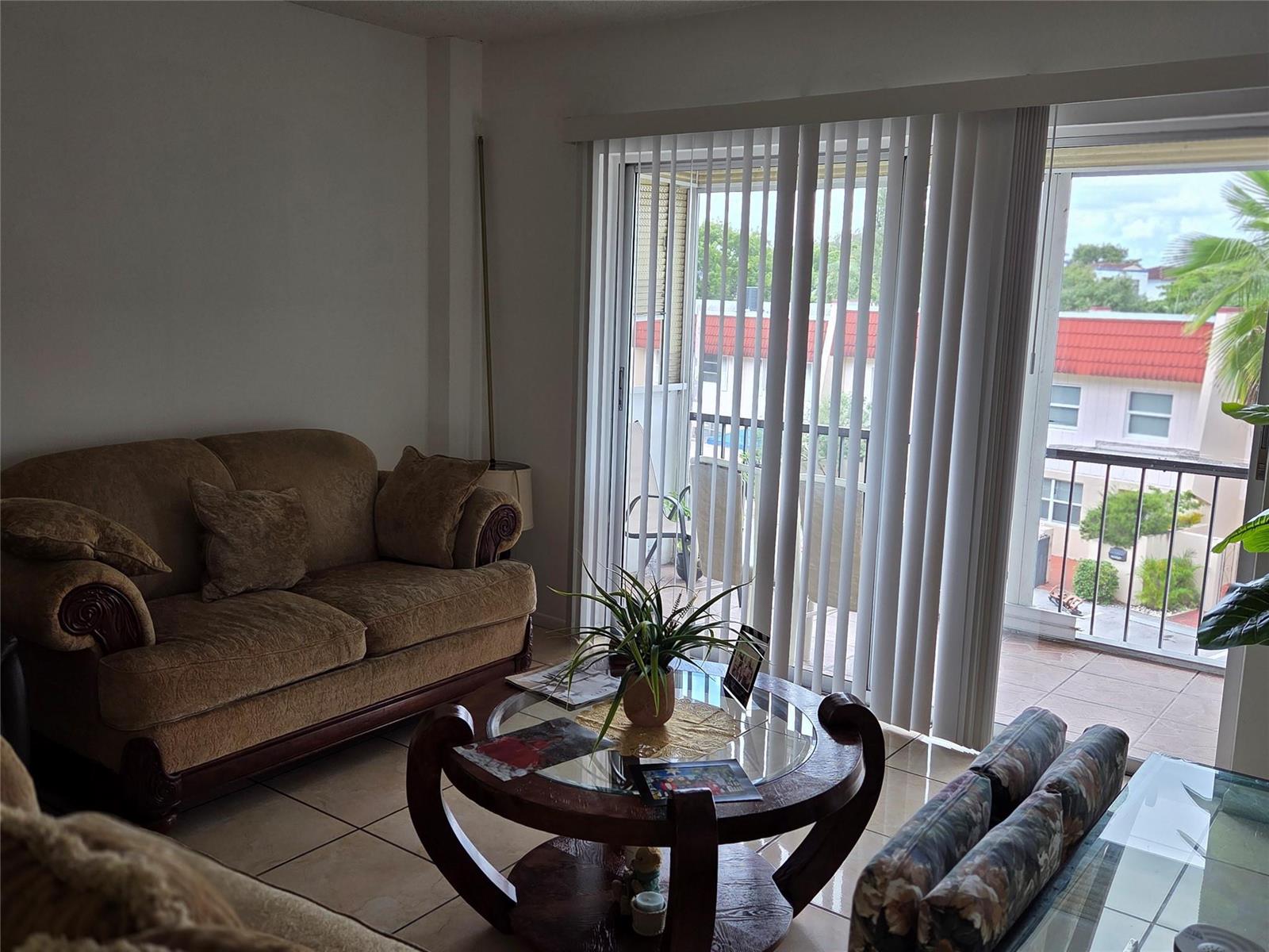 A living room features a brown sofa, a round glass coffee table, and sliding glass doors — 4152 Inverrary Drive # 310, Lauderhill FL 33319, LAUDERHILL, FL