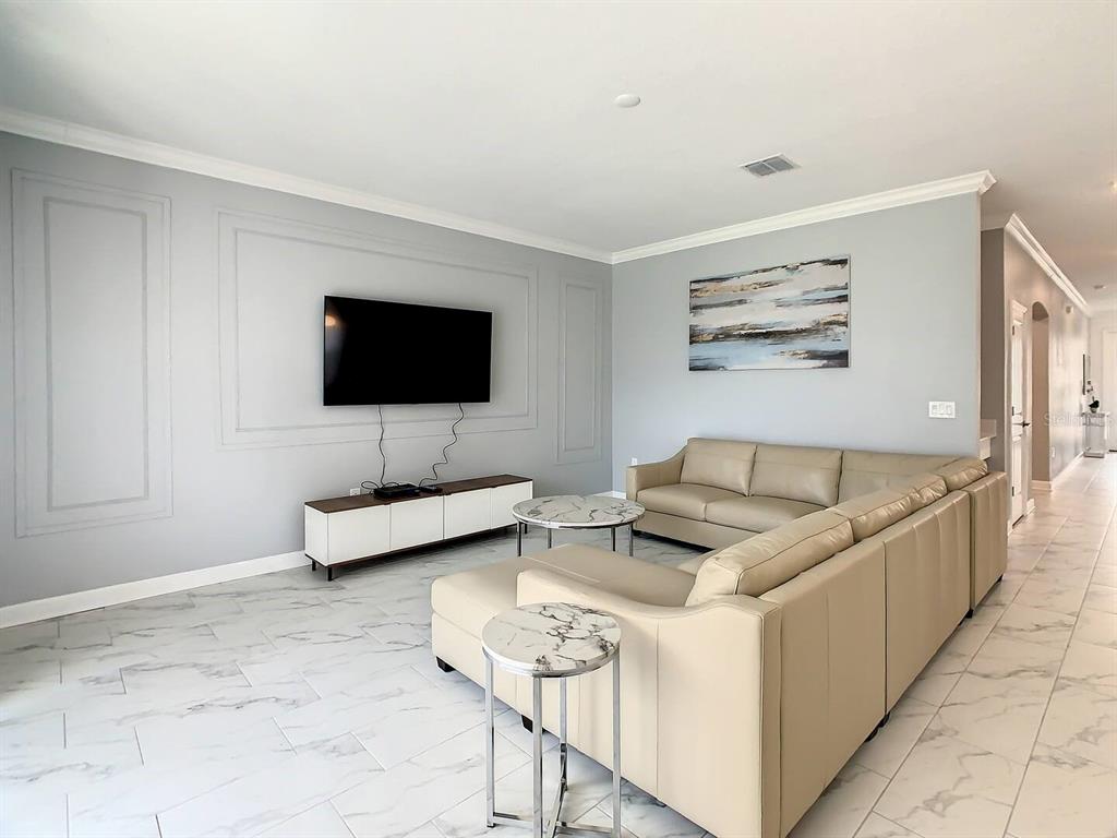 A living room features light gray walls with molding, a sectional sofa, and marble-look tile flooring — 2908 PROTAGONIST STREET, KISSIMMEE, FL