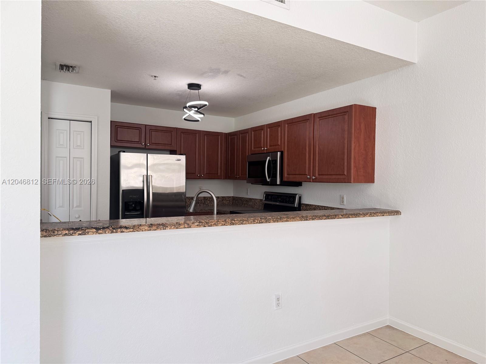 A kitchen features wood cabinets, stainless steel appliances, and a granite-topped breakfast bar — 11102 NW 83rd St # 203, Doral FL 33178, DORAL, FL
