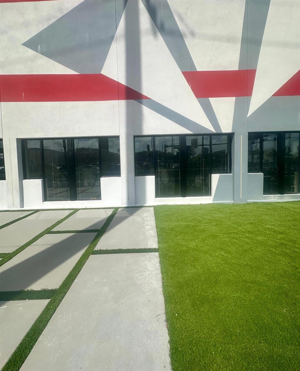 A building exterior features a geometric mural, dark-framed windows, concrete pavers, and artificial turf — 9 N Dixie Highway, Hallandale Beach FL 33009, HALLANDALE BEACH, FL