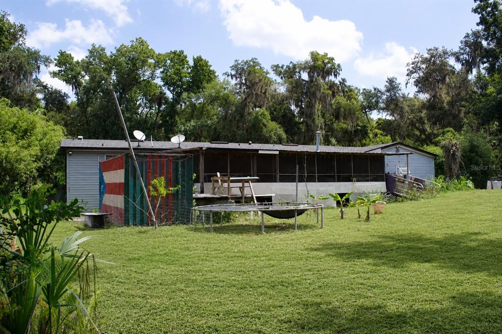 The exterior of a single-story house features a screened-in porch, a trampoline, and a shed — 335 STACY GROVE RD , ROAD, OAK HILL, FL