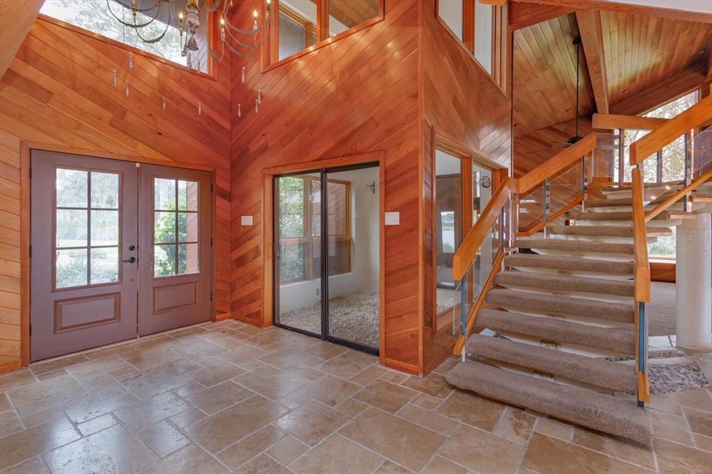 An entryway with stone tile flooring, wood-paneled walls, a staircase, and a double front door — 13377 LAKE BUTLER BOULEVARD, WINTER GARDEN, FL