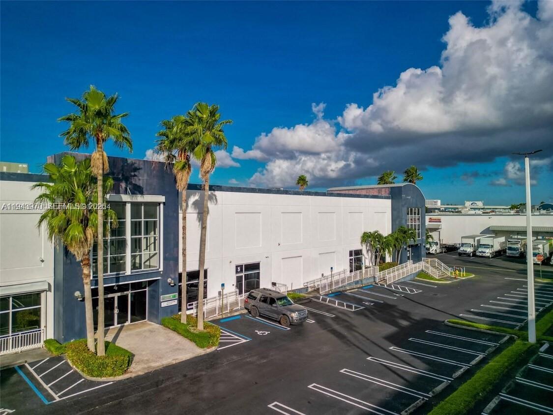 An exterior view of a commercial building with a parking lot and palm trees — 7620 NW 25th St # 4, Miami FL 33122, MIAMI, FL