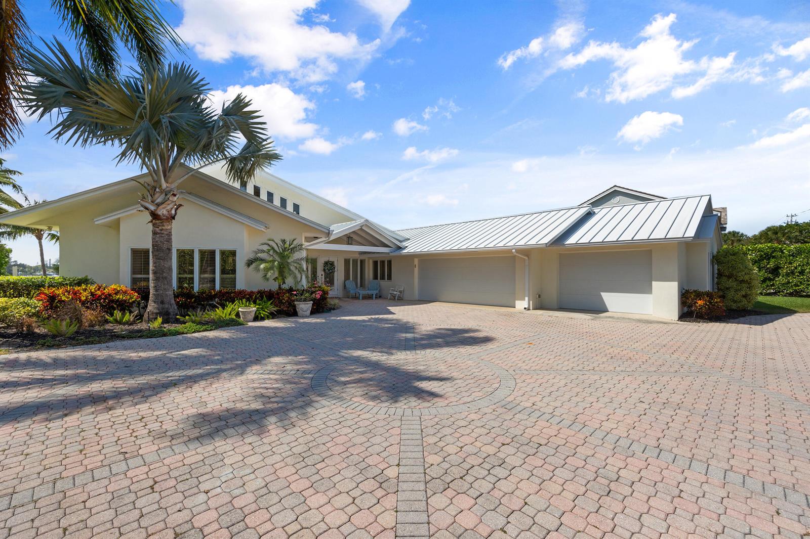 A single-story house with a metal roof and a large circular paver driveway — 163 River Drive, Tequesta FL 33469, TEQUESTA, FL