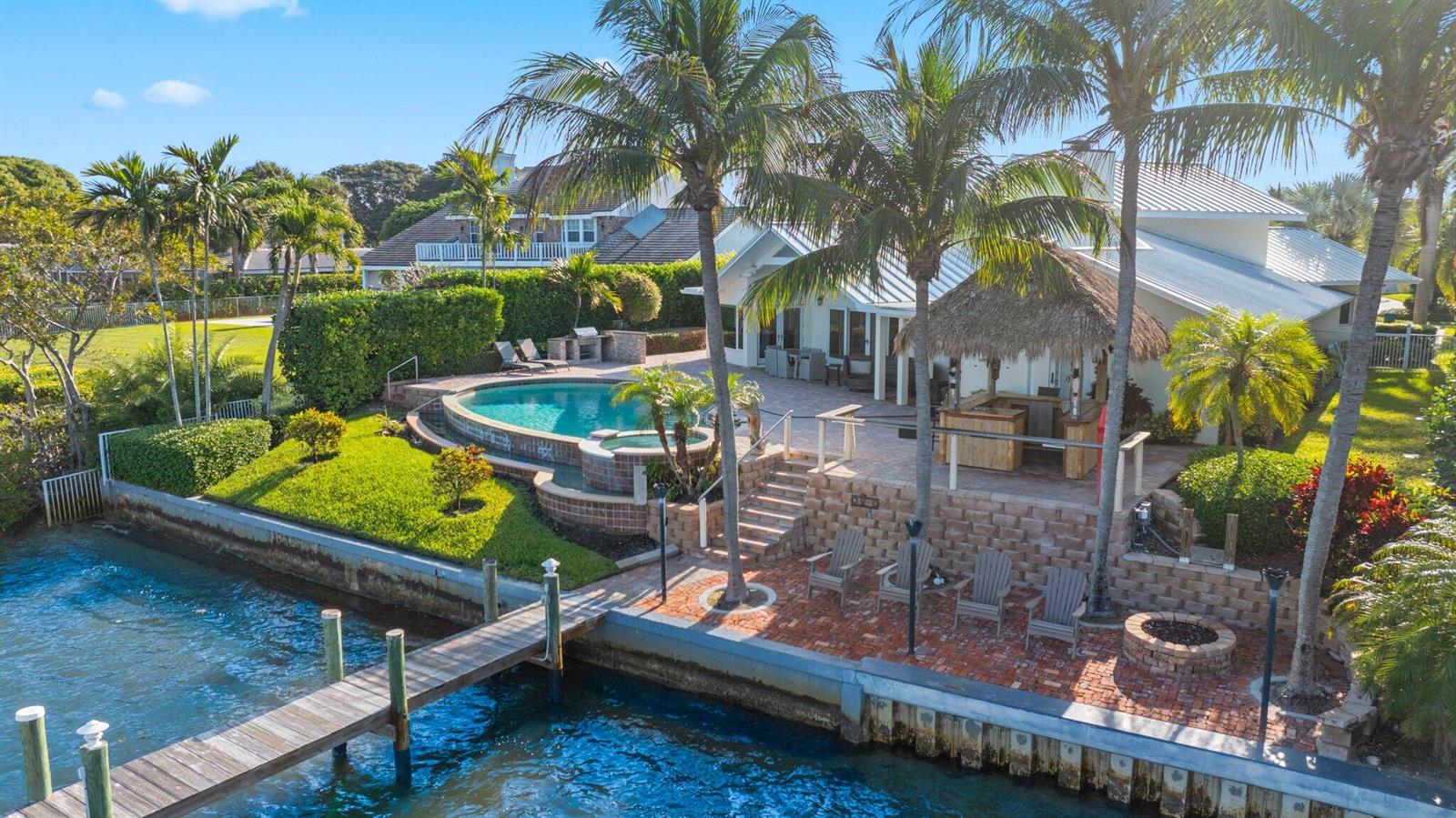 An aerial view of a waterfront home with a pool, tiki bar, and wooden dock — 163 River Drive, Tequesta FL 33469, TEQUESTA, FL