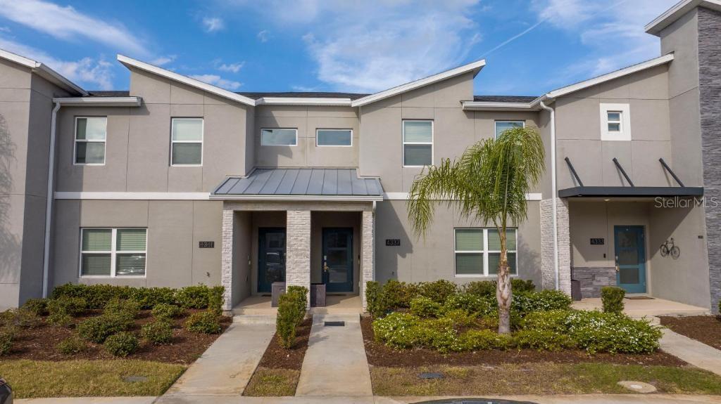 A row of modern two-story townhomes with gray stucco facades and small front gardens — 4337 QUOTE STREET, KISSIMMEE, FL