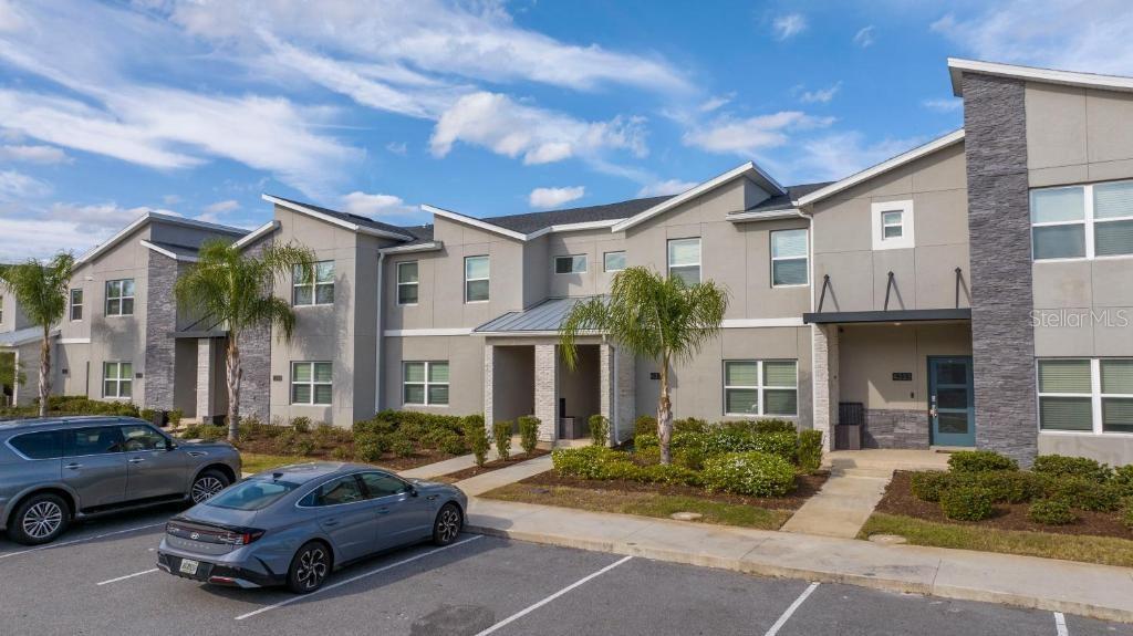 A multi-unit residential building with gray stucco siding, stone accents, and a parking lot — 4337 QUOTE STREET, KISSIMMEE, FL