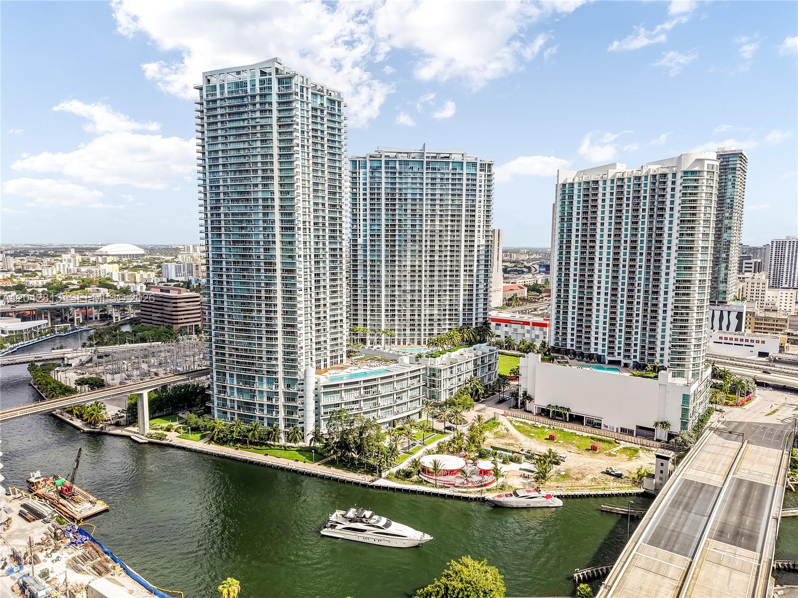 An aerial view shows three tall residential towers situated along a river with boats — 90 SW 3rd St # 3003, Miami FL 33130, MIAMI, FL