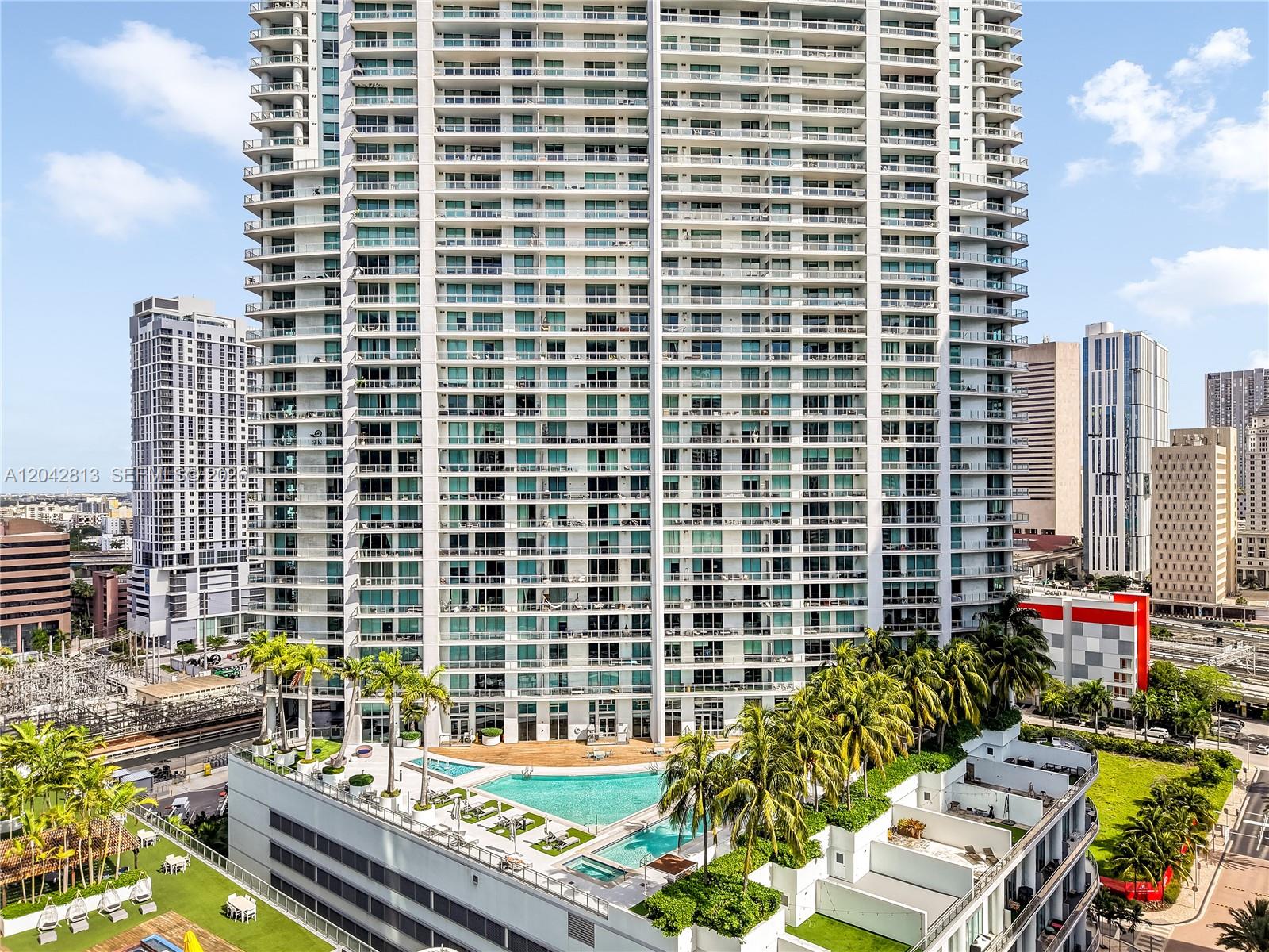 A high-rise residential building features a swimming pool deck with palm trees on its podium — 90 SW 3rd St # 3003, Miami FL 33130, MIAMI, FL