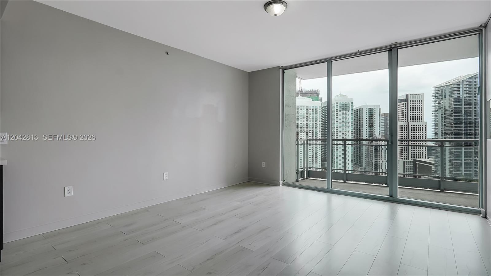 An empty room with light gray walls, wood-look flooring, and a large balcony overlooking city skyscrapers — 90 SW 3rd St # 3003, Miami FL 33130, MIAMI, FL