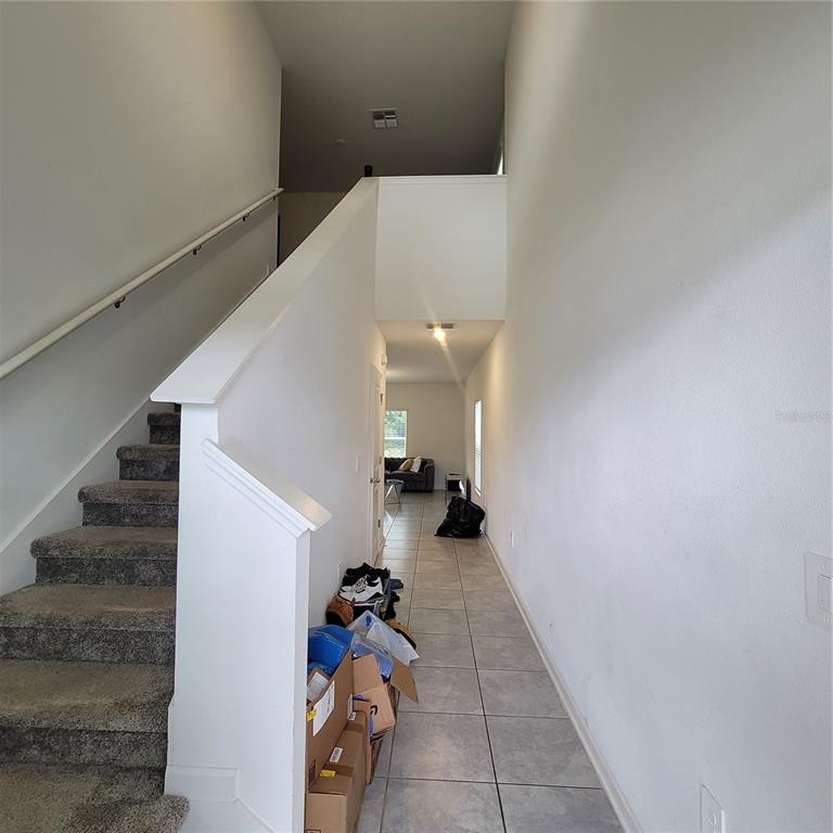A hallway with tiled floors leads to a living area past a carpeted staircase — 577 BELL PRAIRIE CIRCLE, LAKE WALES, FL