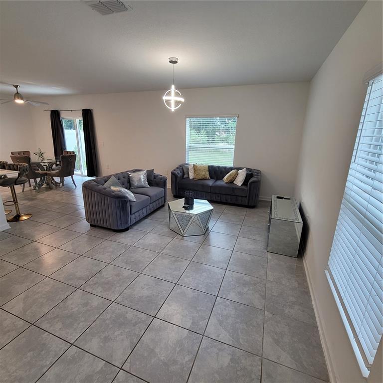 A living room with gray tufted sofas, a mirrored coffee table, and tile flooring — 577 BELL PRAIRIE CIRCLE, LAKE WALES, FL