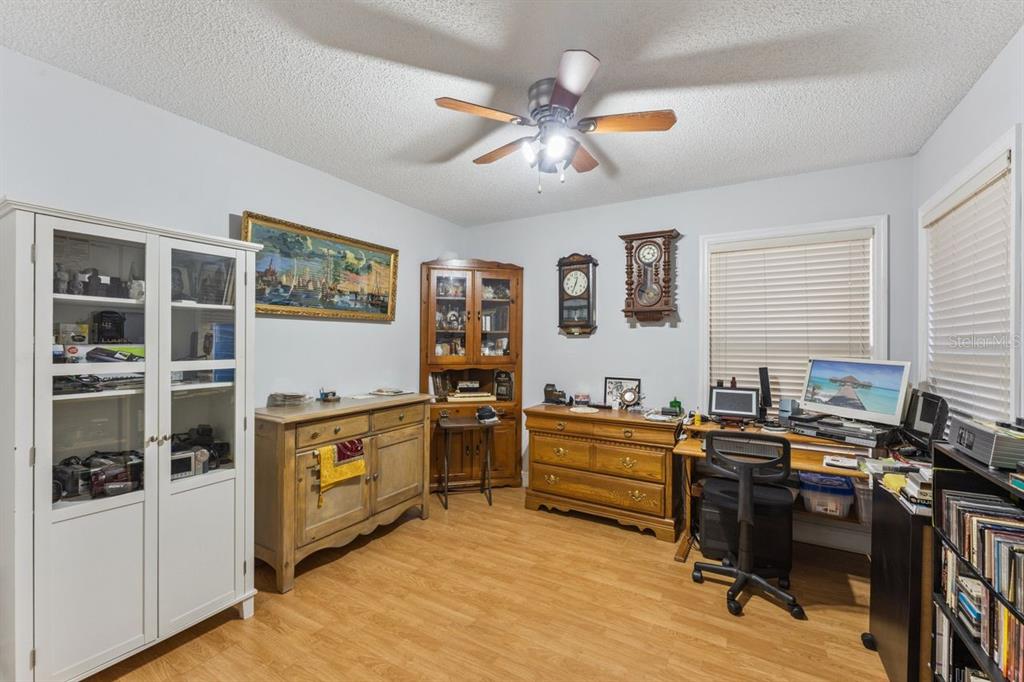 A home office with wood-look flooring, a ceiling fan, storage cabinets, and a computer desk — 8215 ROLLA COURT, ORLANDO, FL