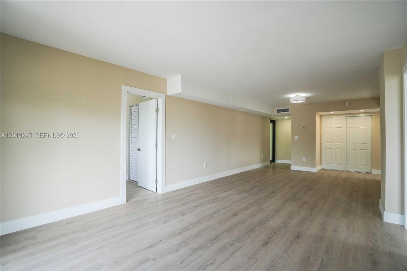 An empty room features light-colored wood-look flooring, beige walls, and a white closet — 6960 Rue Vendome # 201, Miami Beach FL 33141, MIAMI BEACH, FL
