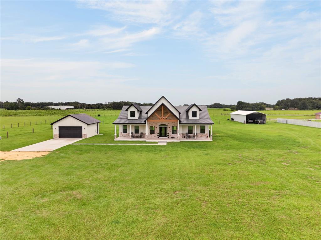 A modern farmhouse with a metal roof sits on a large, grassy rural lot — 7309 BUSTED OAKS WAY, BUSHNELL, FL