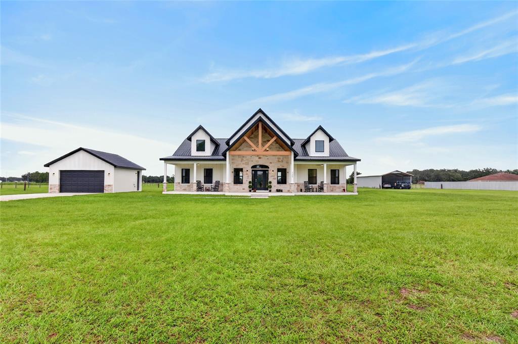 A modern farmhouse with a stone facade, metal roof, and a detached garage — 7309 BUSTED OAKS WAY, BUSHNELL, FL